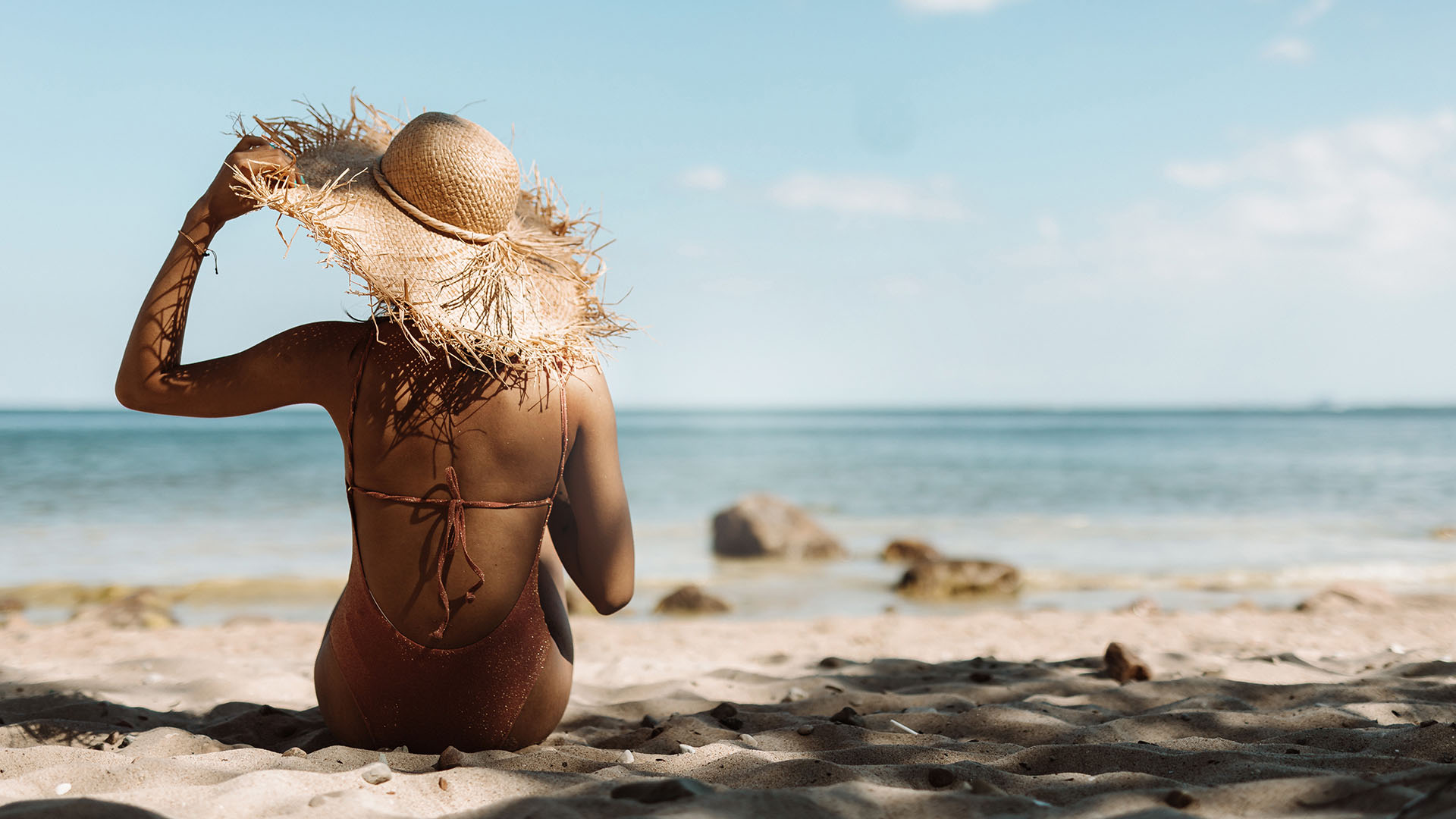 Elite Havens - A woman sitting on the shore